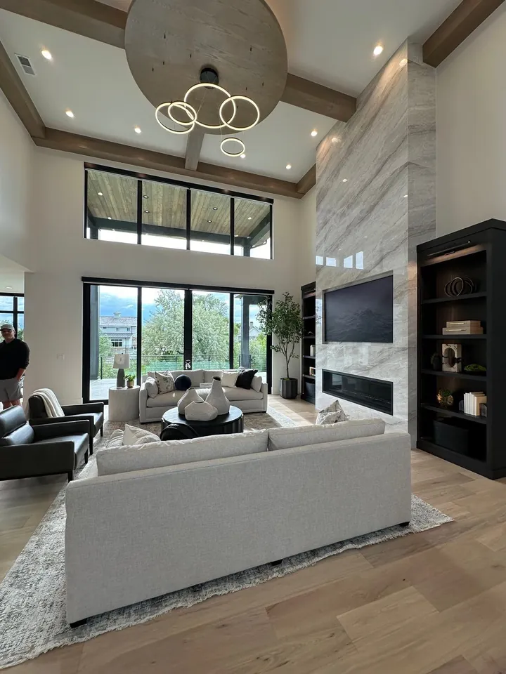 Double-height living room with a stone fireplace, wood beams and large windows