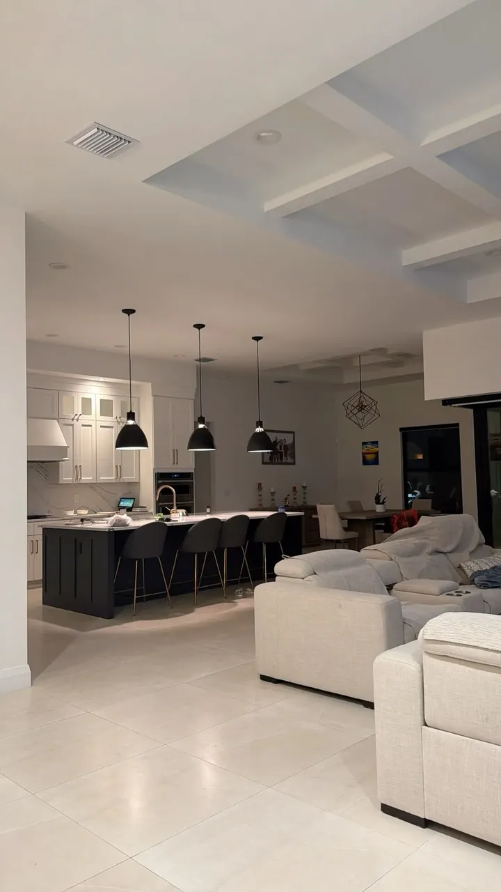 Open-plan space with a coffered ceiling, pendant lights and light tile flooring
